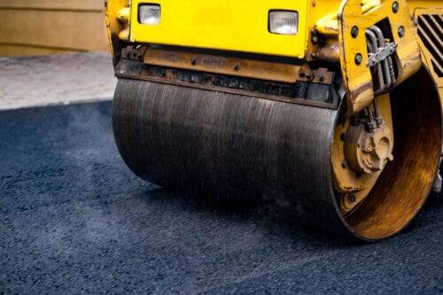 Steamroller flattening out asphalt.